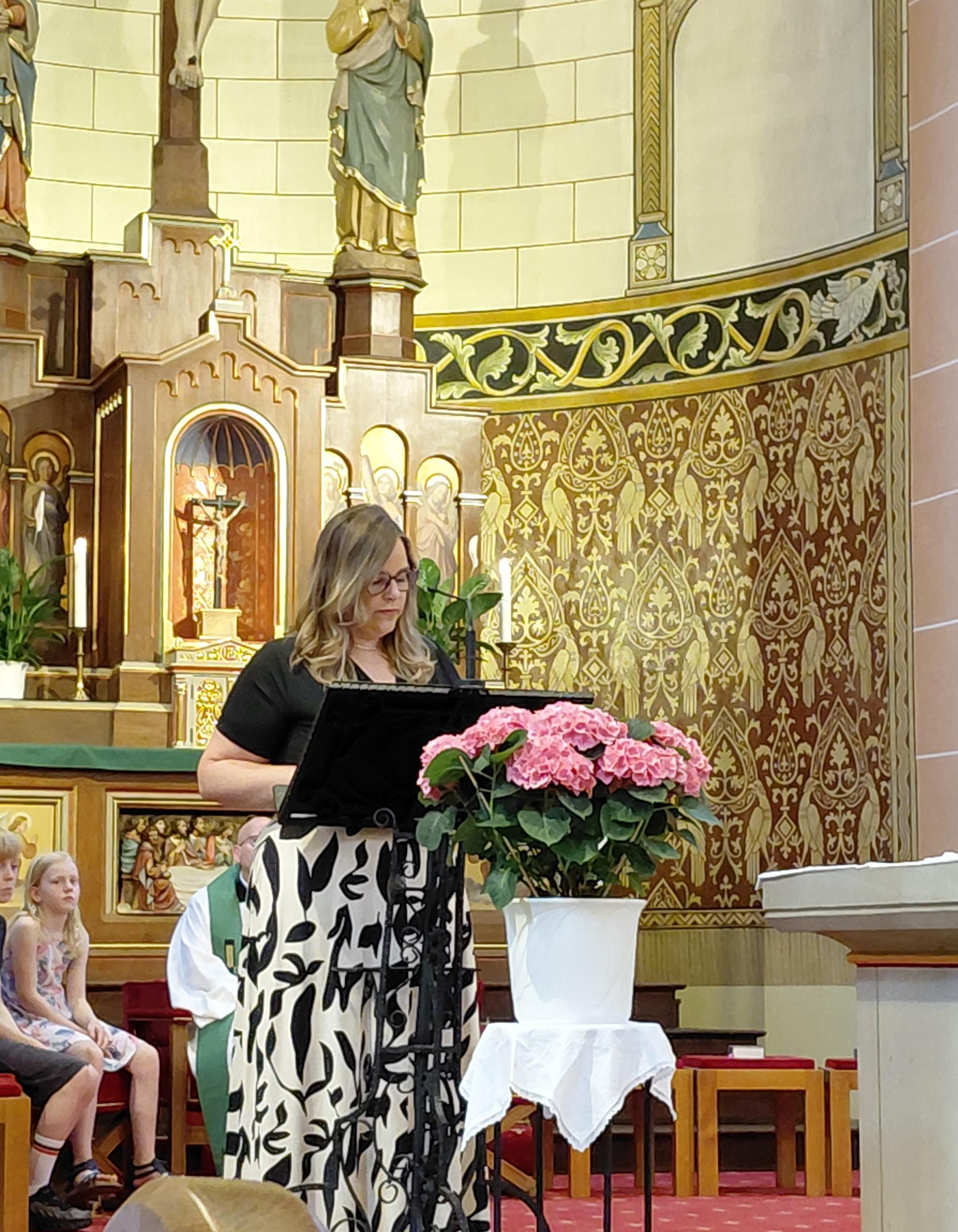 Frau Schneider steht am Ambo im Kirchenraum der Kirche in Dieblich